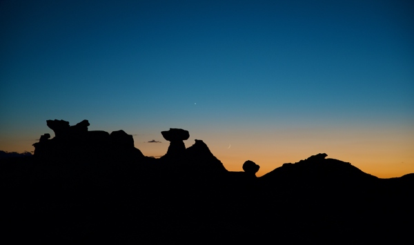 Hoodoos silhouetted at sunset, with a crescent moon and Venus visible in the sky